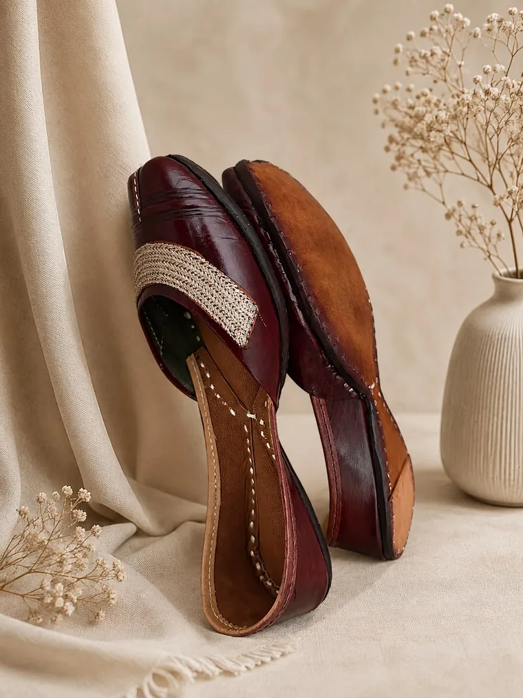 A jutti tipped on its side showing the hand-stitched edge where the sole meets the upper.