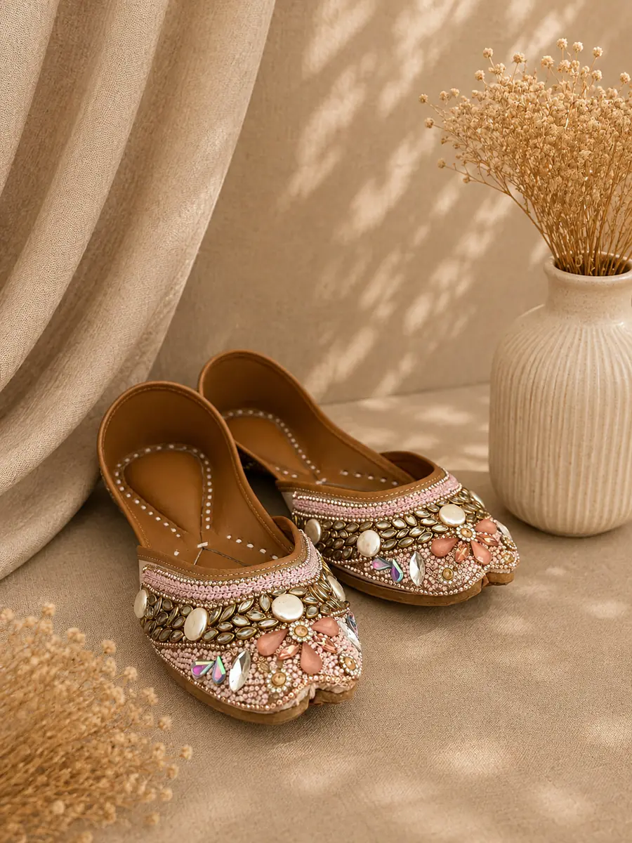 A pair of Blush Royal juttis resting on cream fabric, seen from the side.