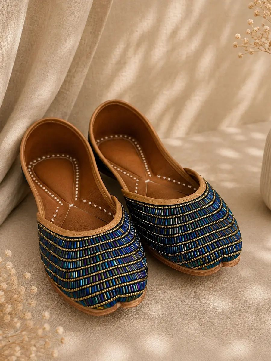 A pair of Neel Noor juttis resting on cream fabric, seen from an angle.
